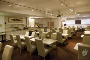 a dining room with tables and chairs and a kitchen at Hotel Quickborn & Gästehaus Hesse in Quickborn