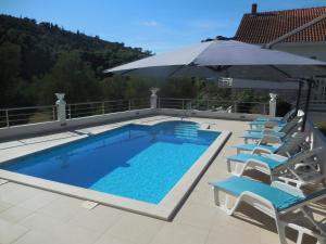 a swimming pool with chairs and an umbrella at White House Lopud,Dubrovnik in Lopud