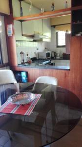 cocina con mesa de cristal y sillas blancas en Tejas Verdes Alojamiento Familiar, en Villa Gesell
