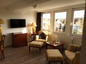 a living room with two chairs and a tv at Hotel De Insulåner in Langeoog