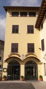 a yellow building with brown shuttered windows on it at Hotel La Meridiana in Anghiari