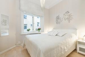 biała sypialnia z białym łóżkiem i oknem w obiekcie Go Happy Home Apartments w Helsinkach