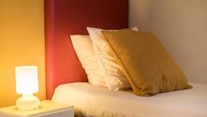 a bed with a pillow and a lamp on a table at Cottage "Les MARAIS" à quelques pas du Lac de la forêt d'Orient - Les Cottages du Belvédère in Mesnil-Saint-Père
