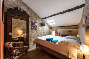 1 dormitorio con 1 cama grande y pared de piedra en Château Croix Beauséjour "Maison du Vigneron", en Montagne