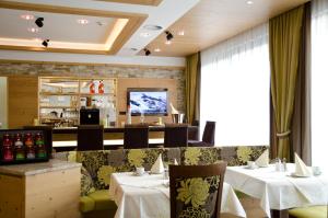 a dining room with tables and chairs and a television at Hotel Garni Arosa in Ischgl