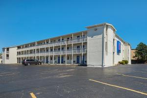 un grand bâtiment blanc avec une voiture garée dans un parking dans l'établissement Motel 6-Blue Springs, MO, à Blue Springs