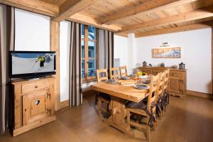 a dining room with a wooden table and a television at Le Kursaal Apartment - Chamonix All Year in Chamonix