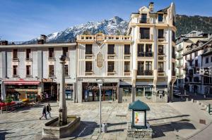 a large building in the middle of a city with mountains at Le Kursaal Apartment - Chamonix All Year in Chamonix