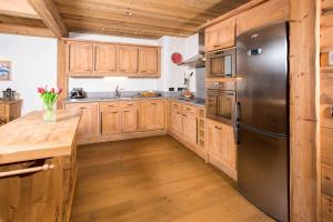 a kitchen with wooden cabinets and a stainless steel refrigerator at Le Kursaal Apartment - Chamonix All Year in Chamonix