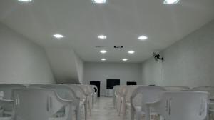 a room with rows of white chairs and lights at Hotel Canaã Express in Jarinu