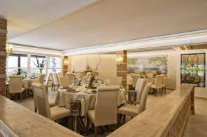 a restaurant with white tables and chairs and windows at Holiday Village in Fondi