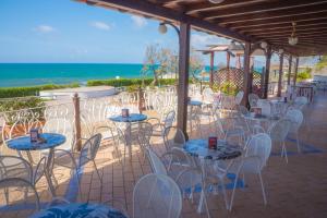 a patio with tables and chairs and the ocean at Holiday Village in Fondi