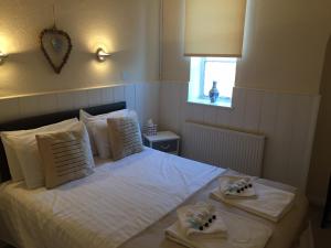 a bedroom with a white bed with towels on it at The Feathers in Dersingham