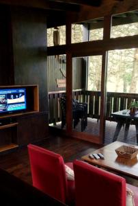 a living room with a television and a table and chairs at Posta Chimango, Cabañas frente al Golf Los Acantilados in Mar del Plata +31 photos