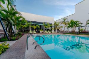 a swimming pool in front of a building with palm trees at Waira Suites in Leticia
