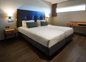ein großes Bett mit blauem Kopfteil in einem Zimmer in der Unterkunft Alcazar Hotel & SPA in Monte Gordo