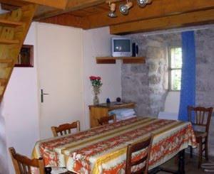 a room with a table with chairs and a tv at Ferme Auberge La Tindelle in La Cresse