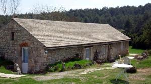 a stone house with a table in front of it at Ferme Auberge La Tindelle in La Cresse