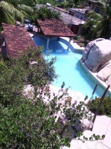 a swimming pool with a rock and blue water at Hotel Paradise Lagoon in El Coacoyul