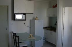 una pequeña cocina con mesa y nevera en Flat em Boa Viagem - Recife, en Recife