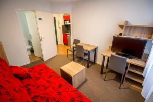 a living room with a bed and a desk with a television at KOSY Appart'hôtel Le Champ De Mars Reims in Reims