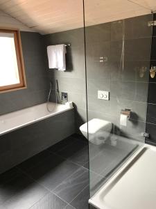 ein Bad mit einer Badewanne, einem WC und einer Dusche in der Unterkunft Hotel Restaurant Zur alten Gasse in Bellwald