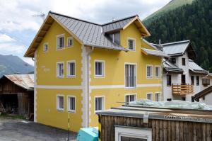 ein gelbes Haus mit einem Dach in der Unterkunft Chasa Alpetta in Samnaun