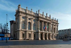 a large building with two flags in front of it at Colazione in Piazza Castello in Turin