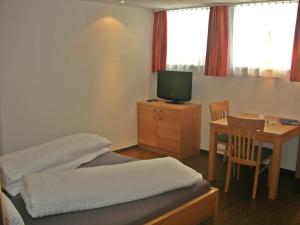 Zimmer mit einem Bett und einem Tisch mit einem TV in der Unterkunft Chasa Alpetta in Samnaun
