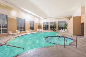 a pool in a hotel room with chairs and tables at Baymont by Wyndham Plymouth in Plymouth