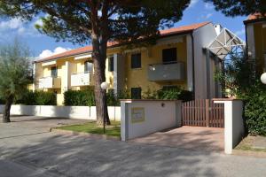 a yellow house with a white gate and a tree at Casa Teresa in Cavallino-Treporti