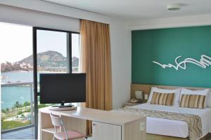 ein Hotelzimmer mit einem Bett und einem Schreibtisch mit einem Computer in der Unterkunft Praia do Canto Apart Hotel in Vitória