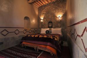 a bedroom with a bed in a stone wall at Auberge Ibrahim in Agoudal