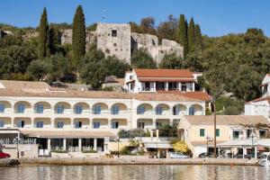 a large white building next to a body of water at Villa Perris Studios in Kassiopi