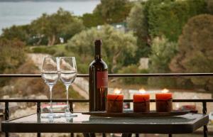 卡西奧皮的住宿－Villa Perris Studios，一瓶葡萄酒和两张带蜡烛的桌子上的玻璃杯