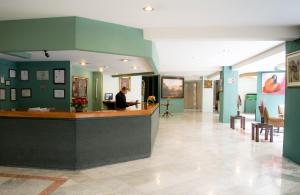 a man standing at a counter in a hospital lobby at Hotel San Francisco in Toluca