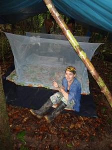 a woman sitting on a mattress in a tent at Lodge Jungle Wolf Expeditions in Yucuruche