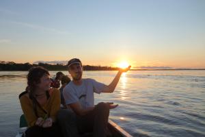 a group of people on a boat on the water as the sun sets at Lodge Jungle Wolf Expeditions in Yucuruche
