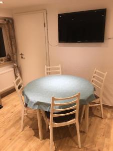 a dining room table with chairs and a television on a wall at Ferienwohnung auf dem Resthof in Aerzen