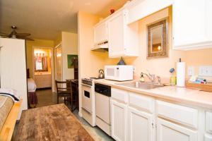 a kitchen with white cabinets and a sink and a table at Barton Hills Condo in Austin