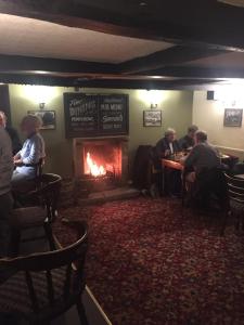 a group of people sitting in a bar with a fireplace at The Punchbowl Inn in Askham