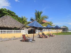 un grupo de sillas y sombrillas en una playa en Beach Hostal Oasis en Las Peñitas