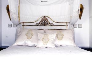 1 cama con cabecero ornamentado y almohadas en Riad Khmisa en Tetuán