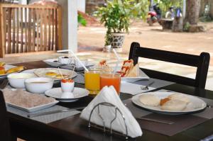 a table with breakfast foods and drinks on it at So-J Beach Villa in Trincomalee