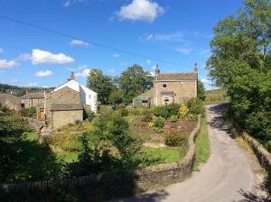 an old stone house with a winding road at Holme House Cottage in Oakworth