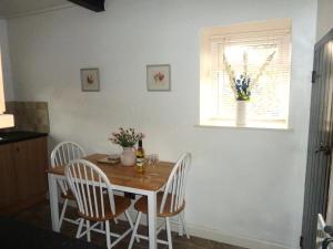 a dining room with a table and chairs and a window at Holme House Cottage in Oakworth