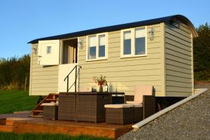 una casa pequeña en una terraza con mesa y sillas en Kerswell Farm Shepherd Huts, en Totnes