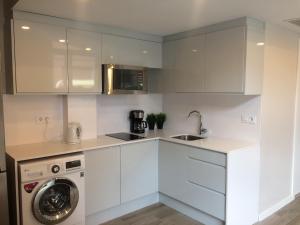 a kitchen with white cabinets and a washing machine at Unique Apartments in Hospitalet de Llobregat