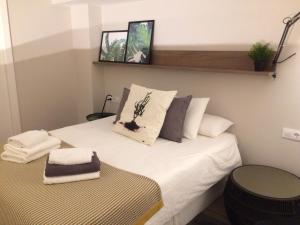 Dormitorio pequeño con cama con sábanas y almohadas blancas en Unique Apartments, en Hospitalet de Llobregat