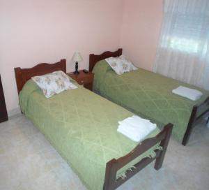 twee bedden in een kamer met groene lakens bij Hosteria Luz de Luna in Valeria del Mar